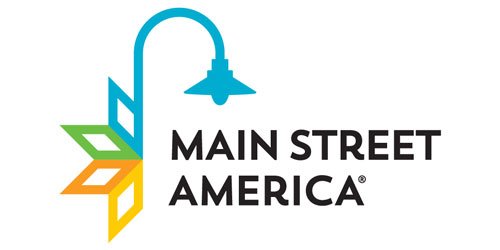 Brightly lit streetlamp with Main Street America logo and colorful leaf graphic representing community and local business support in Apopka, Florida.